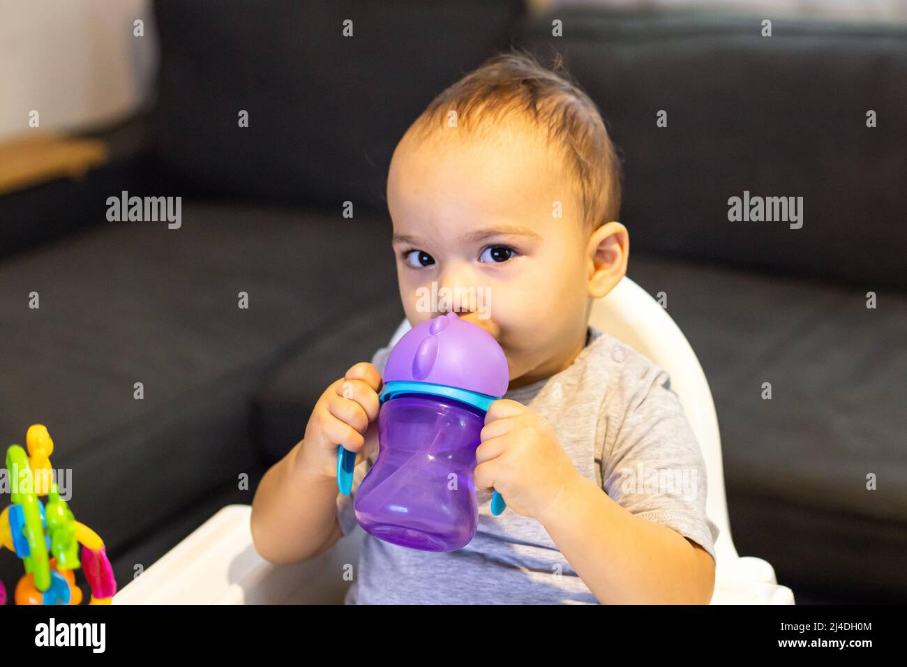 Bambino dolce seduto in seggiolone e acqua potabile dal biberon Foto Stock