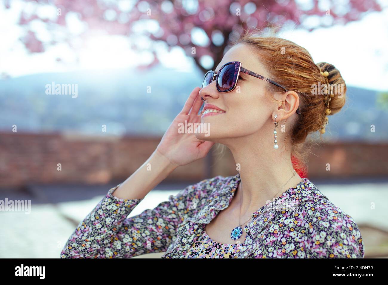 Giovane donna rossa positiva che si gode momenti primaverili nel parco Foto Stock