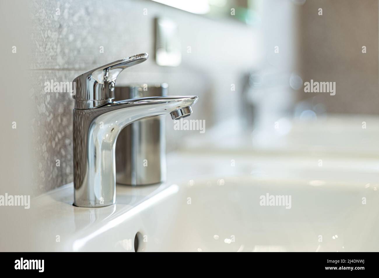 Lavabo moderno con rubinetto cromato (miscelatore acqua) primo piano. Foto Stock