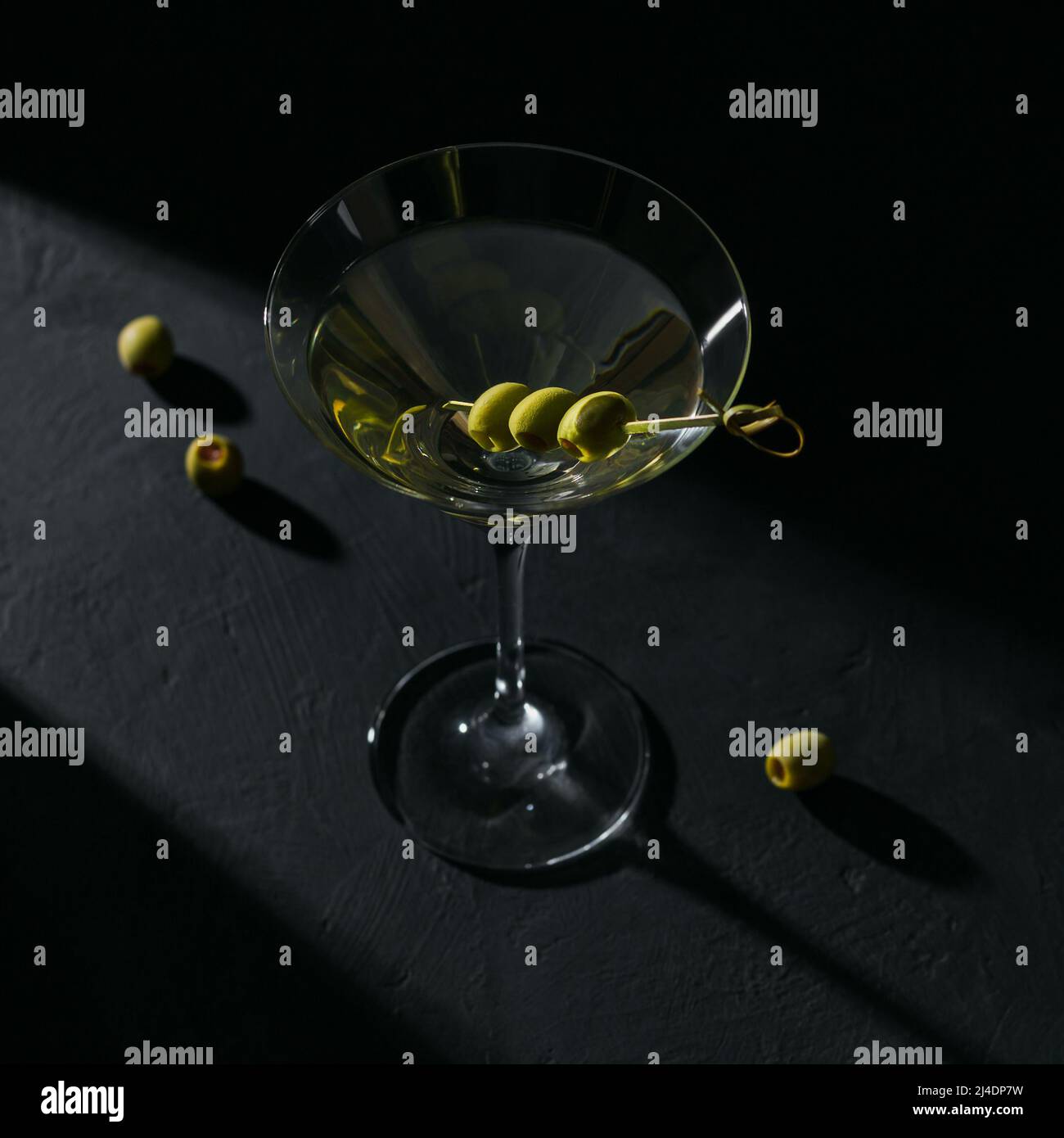 Bicchiere di classico cocktail martini secco con olive su tavola di pietra scura Foto Stock