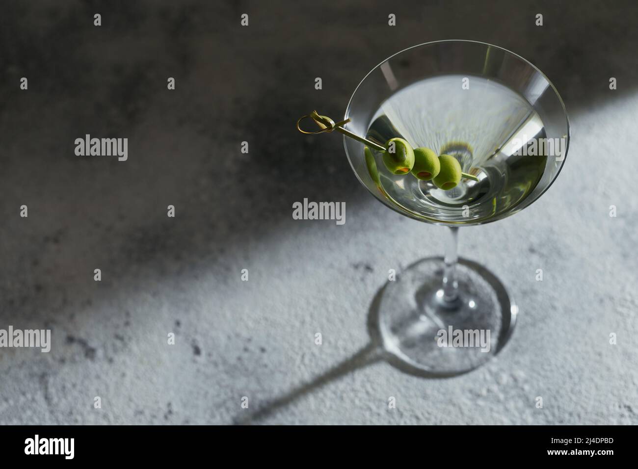 Bicchiere di classico cocktail martini secco con olive su sfondo di pietra grigia. Foto Stock
