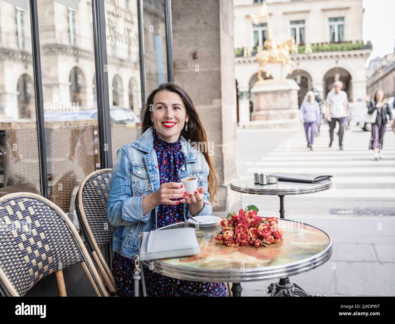 Donna attraente con lunghi capelli seduti in strada caffè e bere caffè Foto Stock