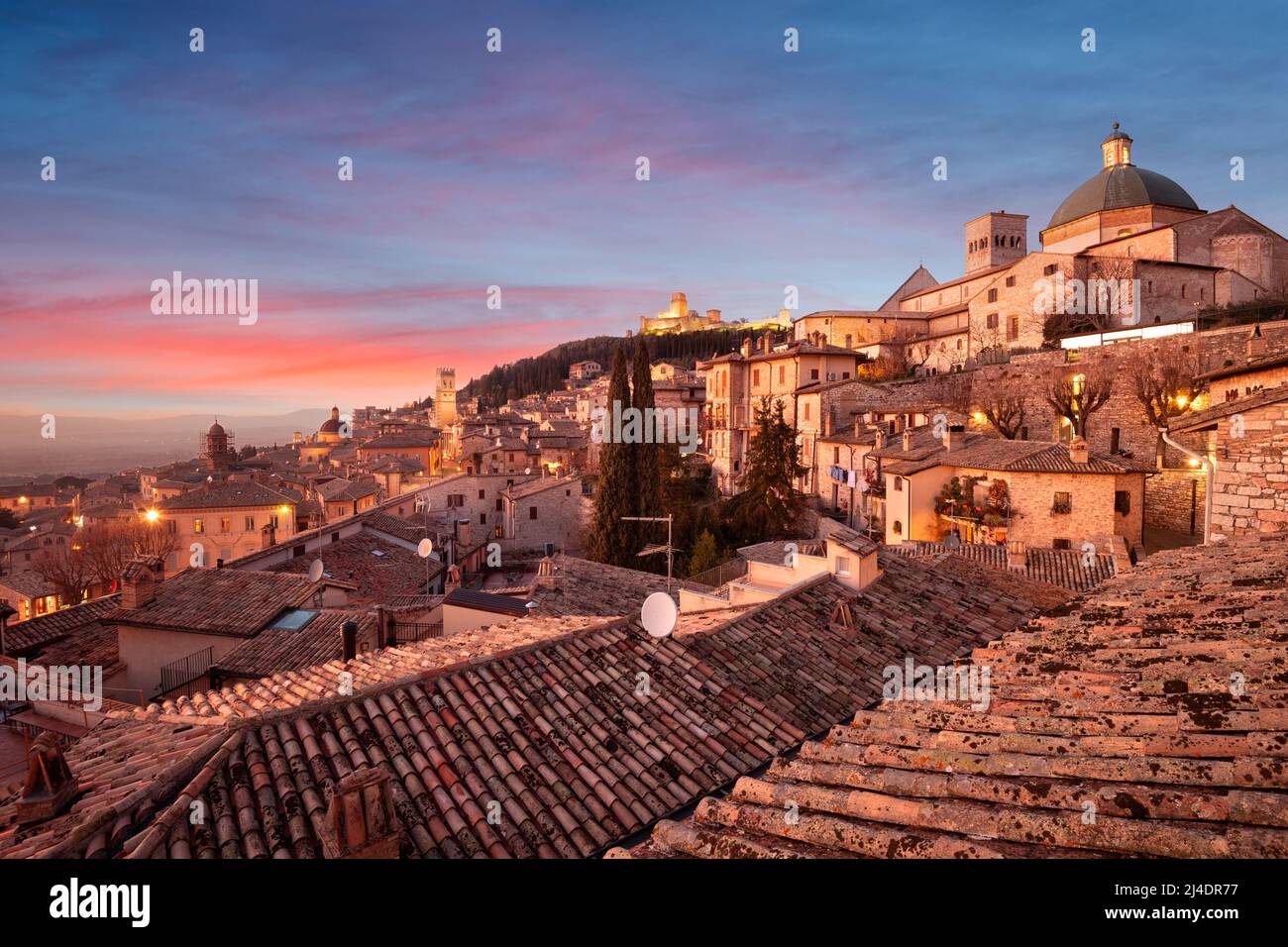 Assisi, Italia tetto collina skyline della città vecchia al crepuscolo. Foto Stock