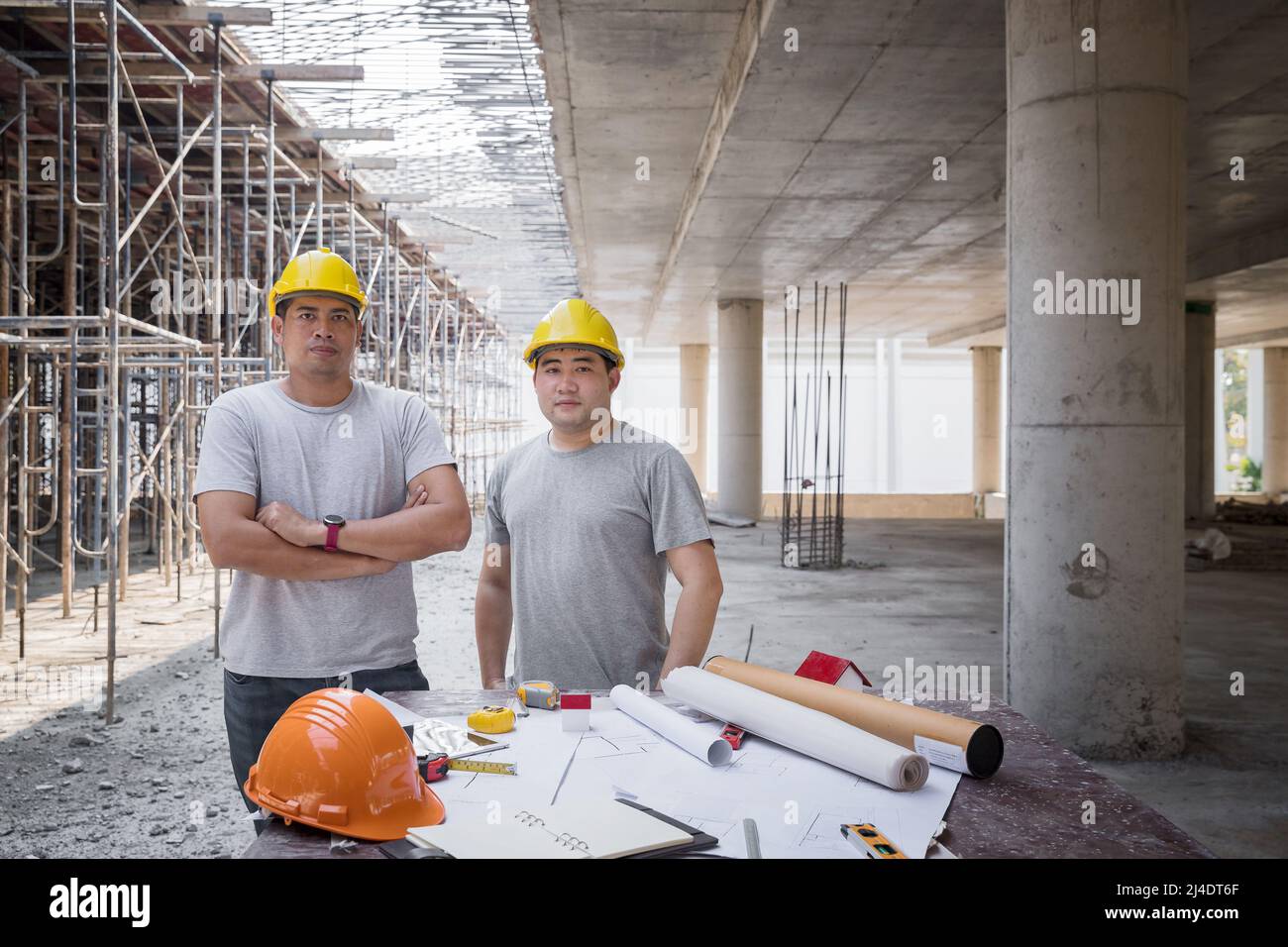 Team sicuri di architetti, ingegneri, appaltatore o responsabile delle costruzioni affiancati di fronte a una scrivania di un cantiere. Foto Stock