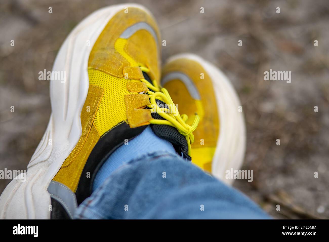 Sneakers gialli decorati con margherite nel parco. Sneakers gialli. Foto Stock
