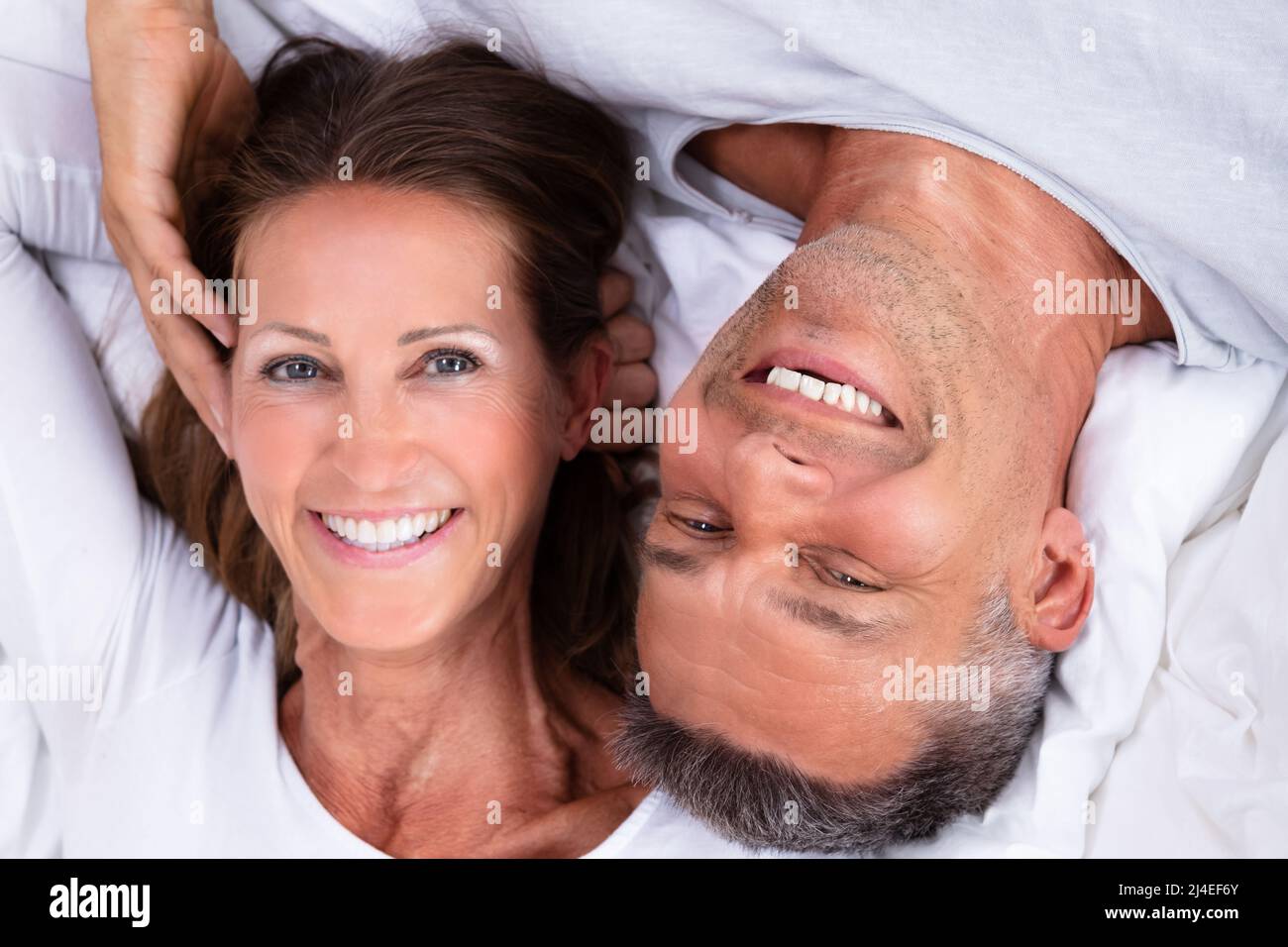 Angolo di Alta Vista di Felice Coppia Matura giacente sul letto Foto Stock