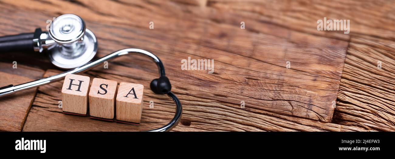 Il sistema HSA Health Conto di risparmio dei blocchi di legno vicino a uno stetoscopio sul tavolo di legno Foto Stock