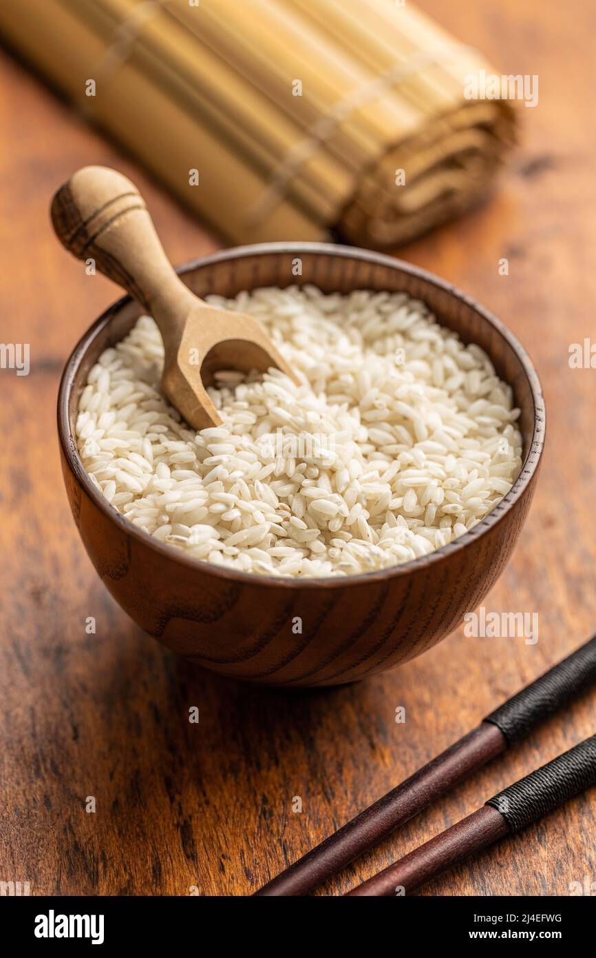 Risotto Carnaroli crudo in ciotola e cucchiaio di legno sul tavolo da cucina. Foto Stock