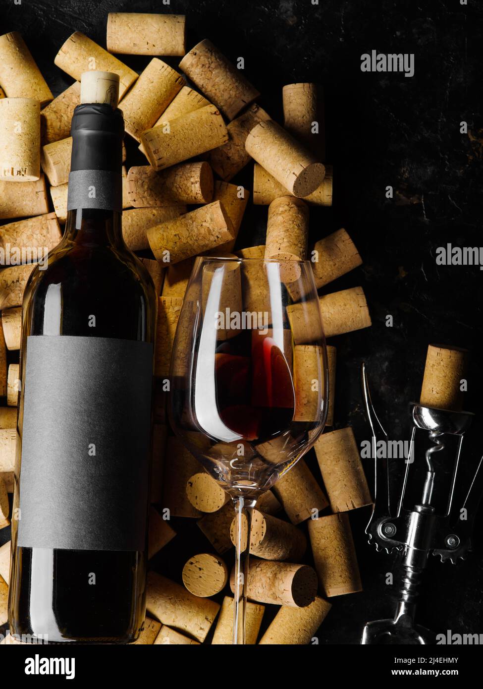 Su sfondo nero ci sono molti tappi di vino, una bottiglia di vino rosso, un cavatappi e un bicchiere di vino con vino. Vacanza, compleanno, anniversario, divieto Foto Stock