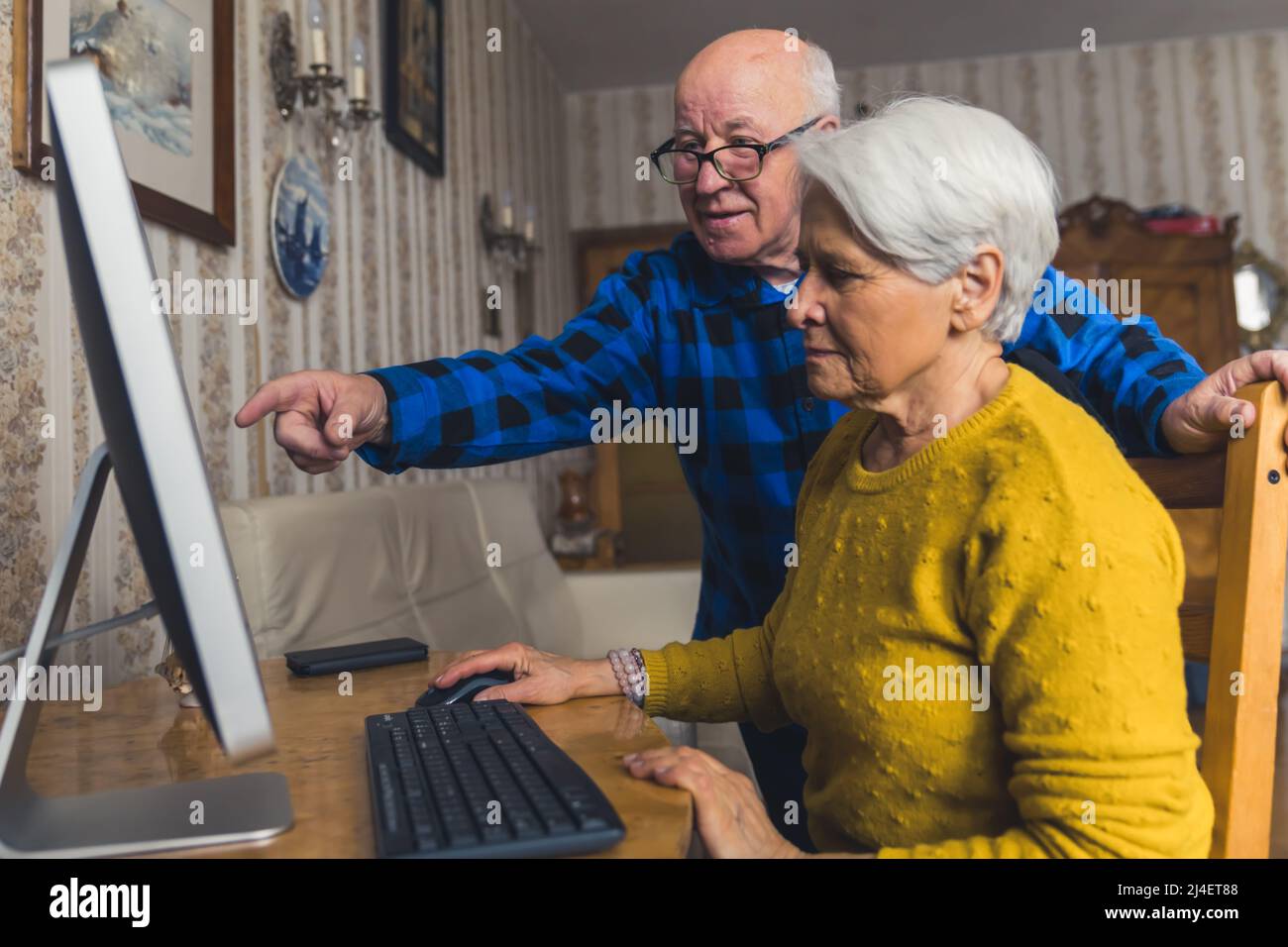 Moderno concetto di anziani. Nonna caucasica impara come usare un computer con l'aiuto del suo marito calvo pensionato. Foto di alta qualità Foto Stock