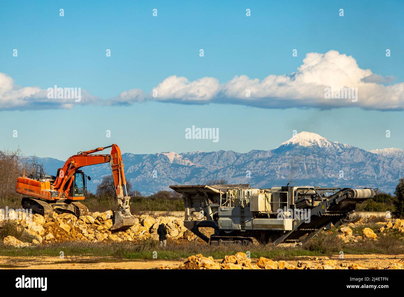 Frantumatore pieno di pietra con frantumatore di pietra e benna Foto Stock
