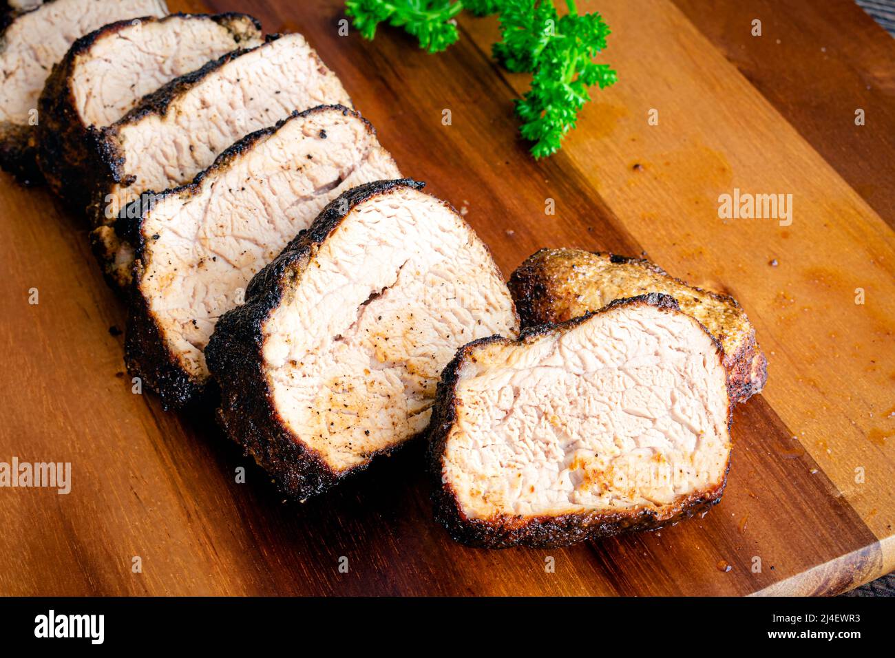 Medaglioni di Tenderloin di maiale arrosto in padella: Fette di succosa filetto di maiale su un tagliere di legno Foto Stock