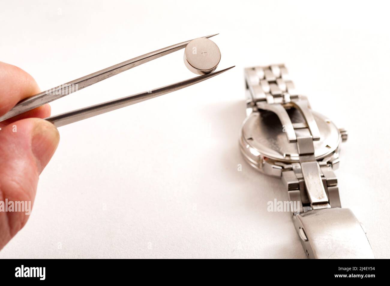 watchmaker sta lavorando per sostituire la batteria su un vecchio orologio al quarzo metallo nel suo negozio di riparazione, egli sta tenendo la nuova batteria in pinzette e ottenere re Foto Stock