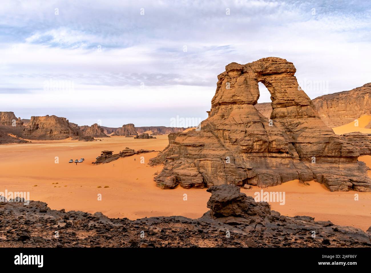 Vista dalla cattedrale di Tamesguida in Tadrart Rouge, Tassili N'Ajjer parco.. Turisti e automobili molto piccoli. Finestra naturale rock. Sabbia e mesa color arancio. Foto Stock