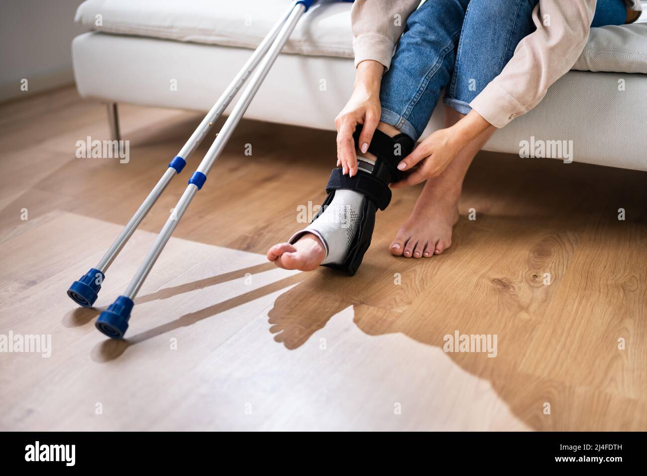 Donna con lesioni alle gambe utilizzando stampelle a casa Foto Stock