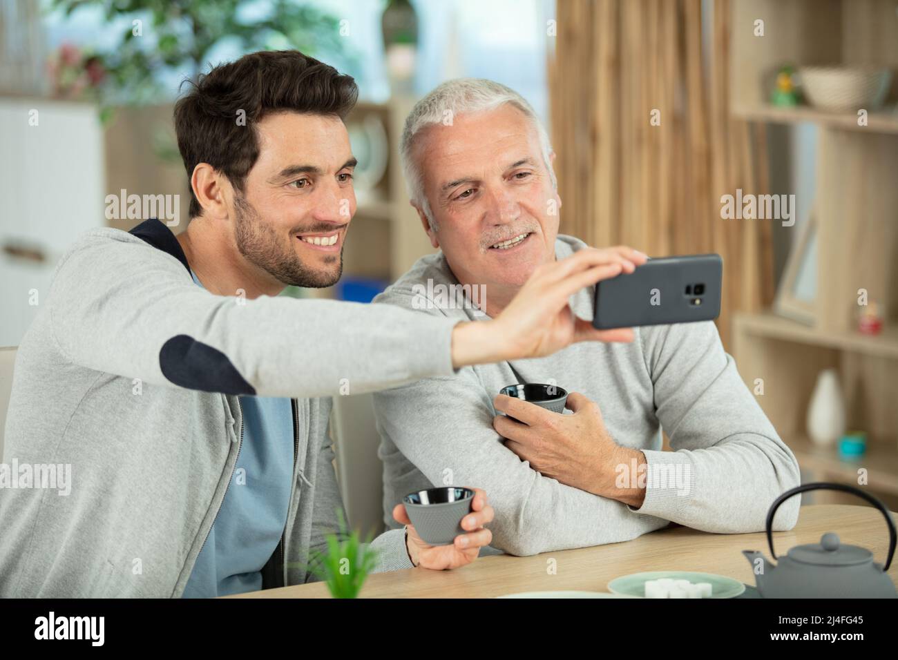figlio adulto con padre anziano che fa selfie Foto Stock