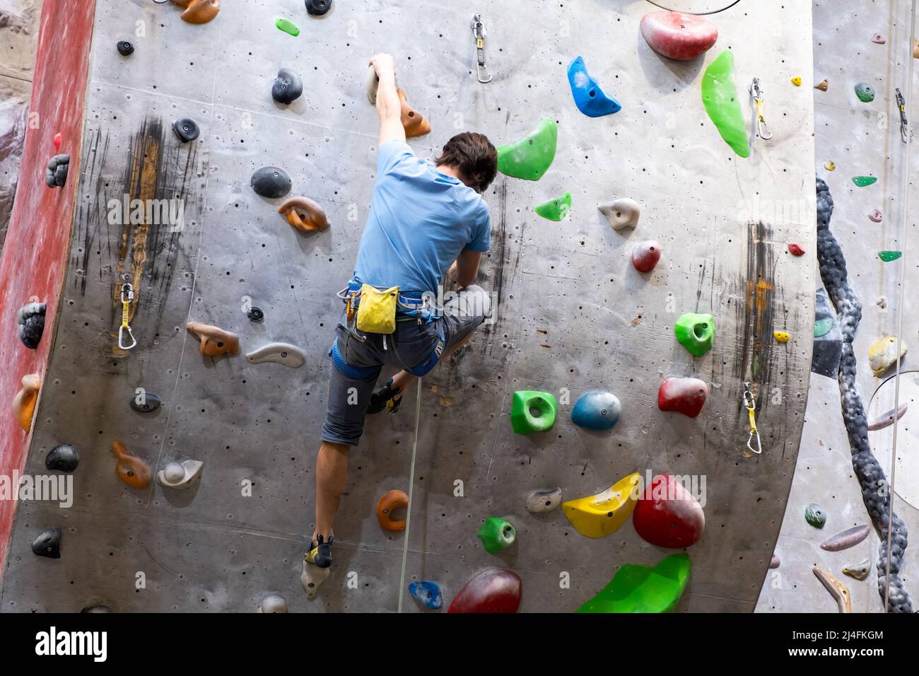 Il climber si allena sul muro di roccia artificiale con assicurazione in palestra di bouldering, aprile 2022, Praga, Repubblica Ceca. Foto Stock
