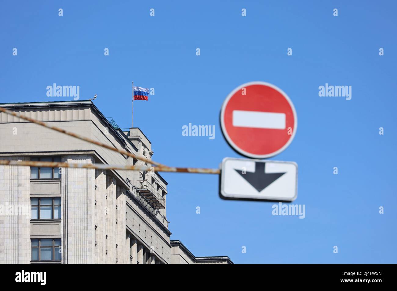 Duma di Stato della Russia con bandiera russa e segnale di stop in primo piano contro il cielo blu. Concetto di sanzioni economiche Foto Stock