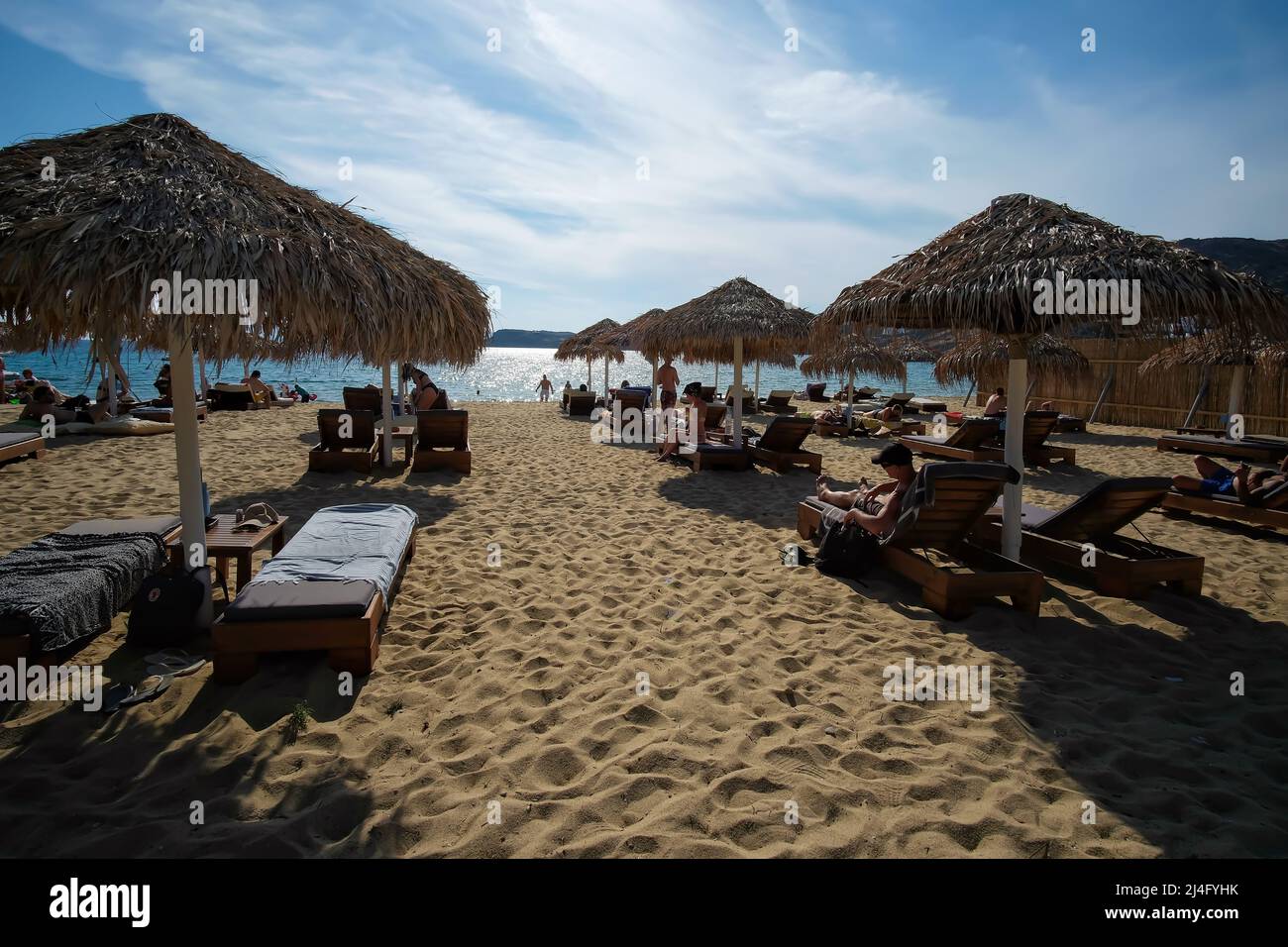 IOS, Grecia - 12 giugno 2021 : turisti che si trovano sui lettini da mare e si godono la splendida e famosa spiaggia di Mylopoatas in iOS Foto Stock