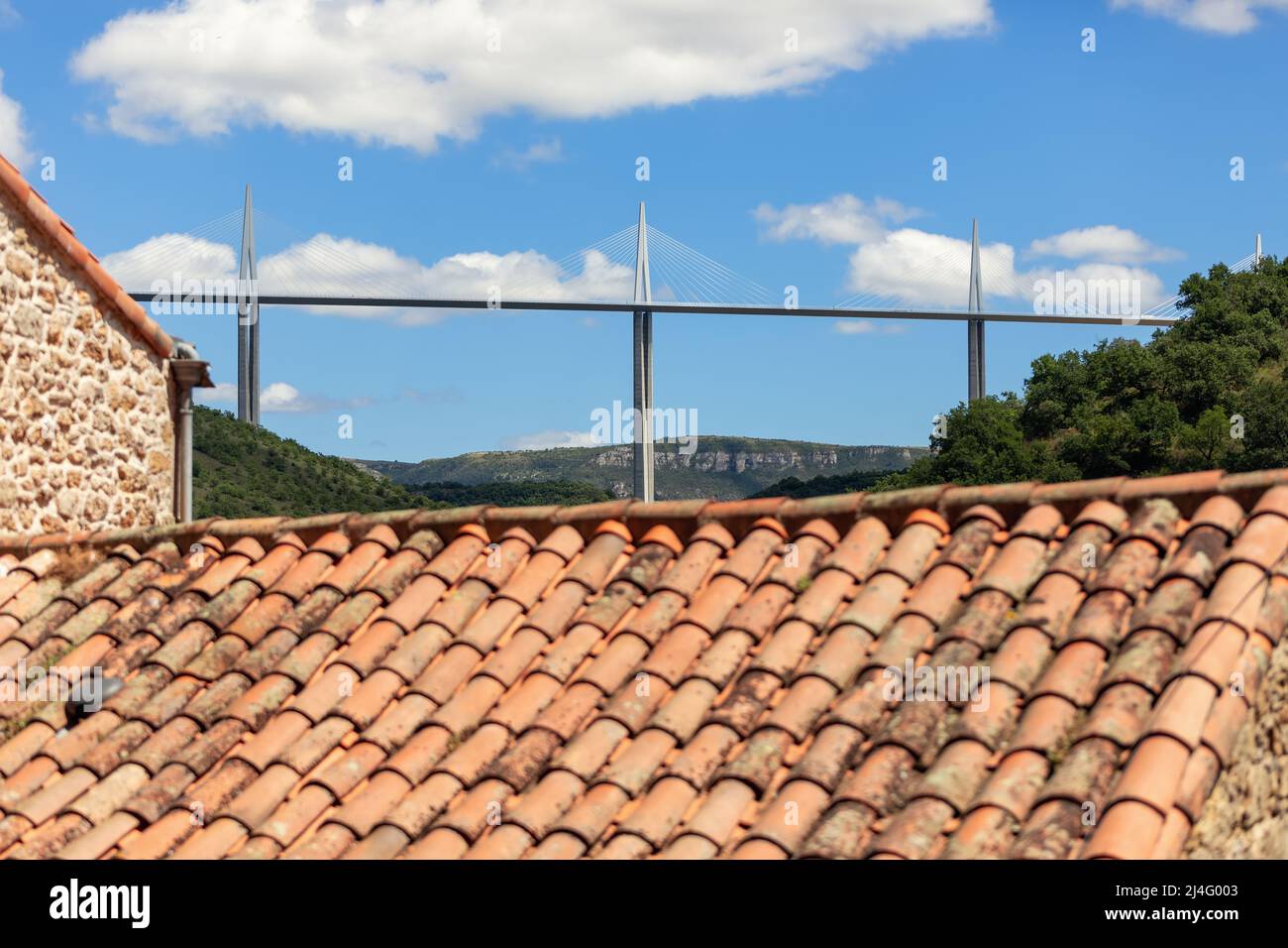 Tetto piastrellato e muro di pietra del Medioevo e Viadotto Millau del 21 secolo. Aveyron, Occitania, Francia meridionale Foto Stock