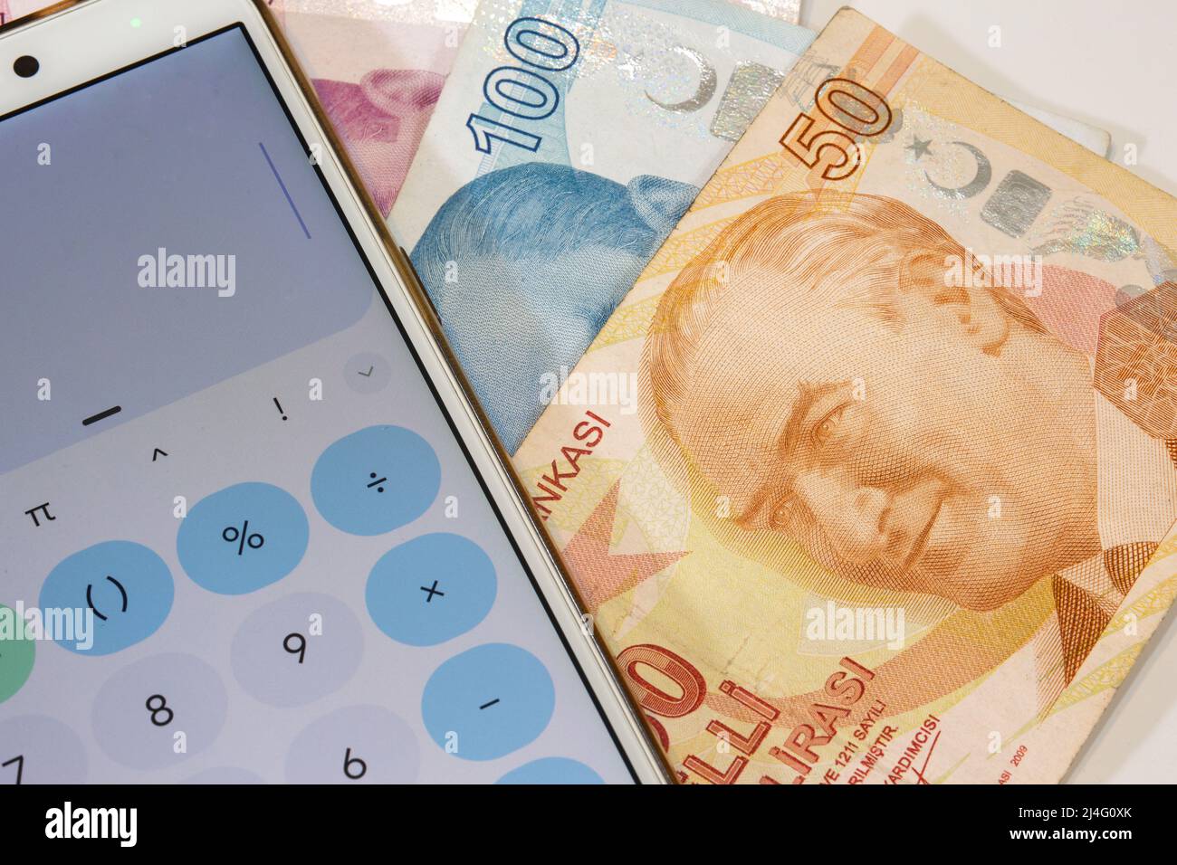 Banconote da 50 e 100 lira turche con l'immagine di Ataturk su di esso e calcolatrice app telefono cellulare aperto su sfondo isolato. Il tempo è concetto di denaro. Foto Stock