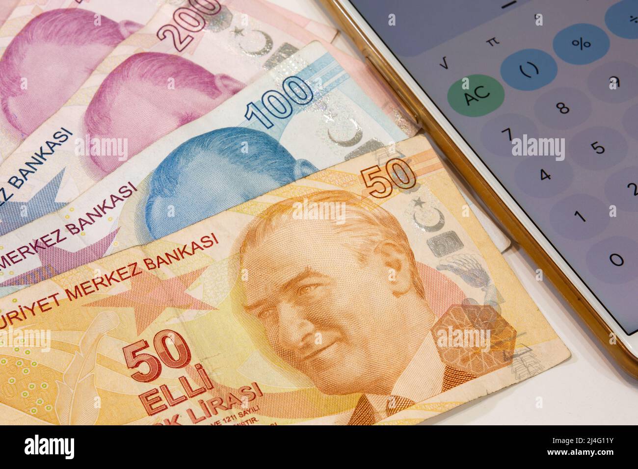 50, 100 e 200 banconote in lira turche e calcolatrice app aprire il telefono cellulare su sfondo isolato. Il tempo è concetto di denaro. Foto Stock