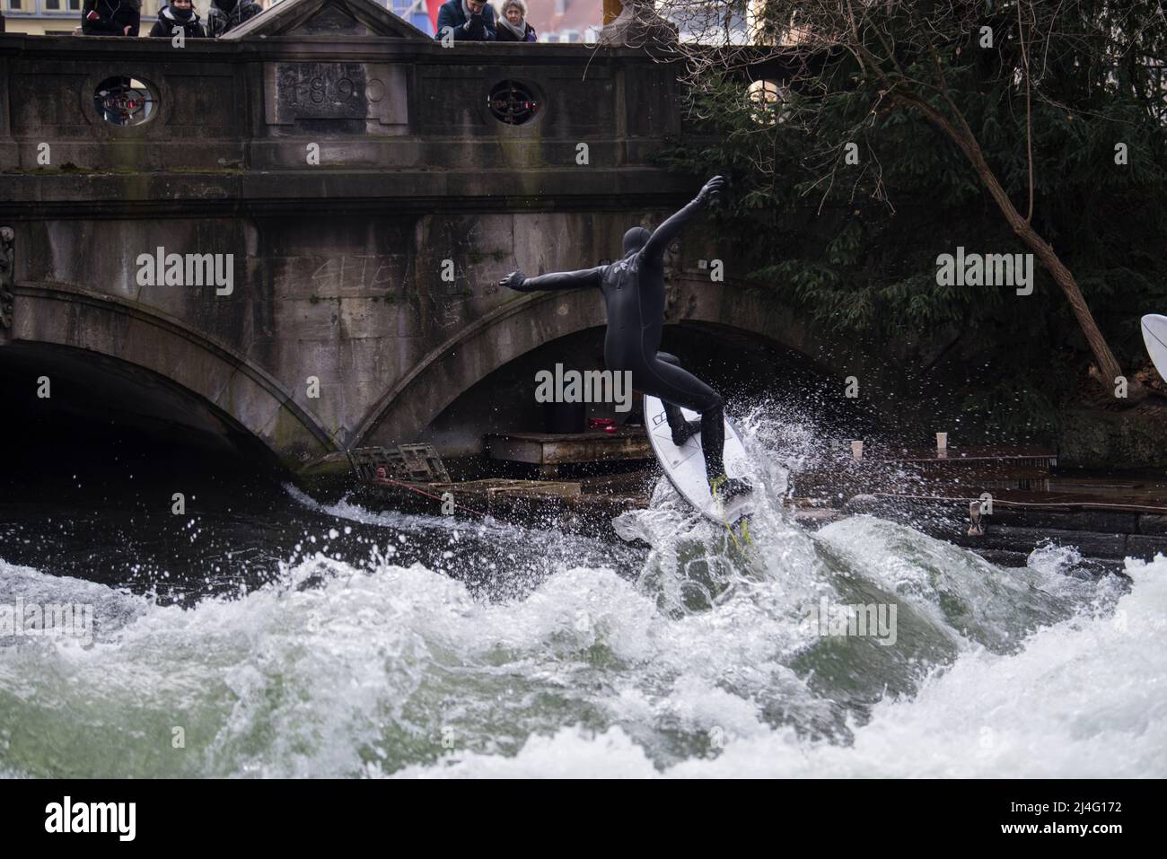 Monaco di Baviera, Germania - 20 dicembre 2021: Surfista nel fiume della città, Monaco è famosa per le persone che navigano in ambiente urbano chiamato Eisbach. Foto Stock