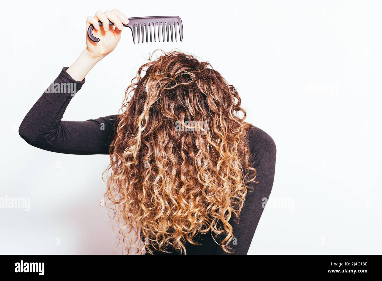 Giovane donna che pettina i capelli ricci spessi con un pettine a denti  larghi Foto stock - Alamy