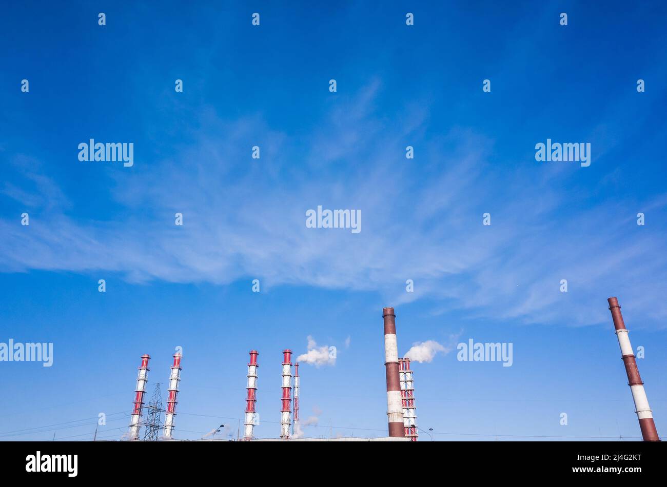 Camini industriali di moderna cogenerazione urbana sono sotto il cielo blu, foto di sfondo Foto Stock