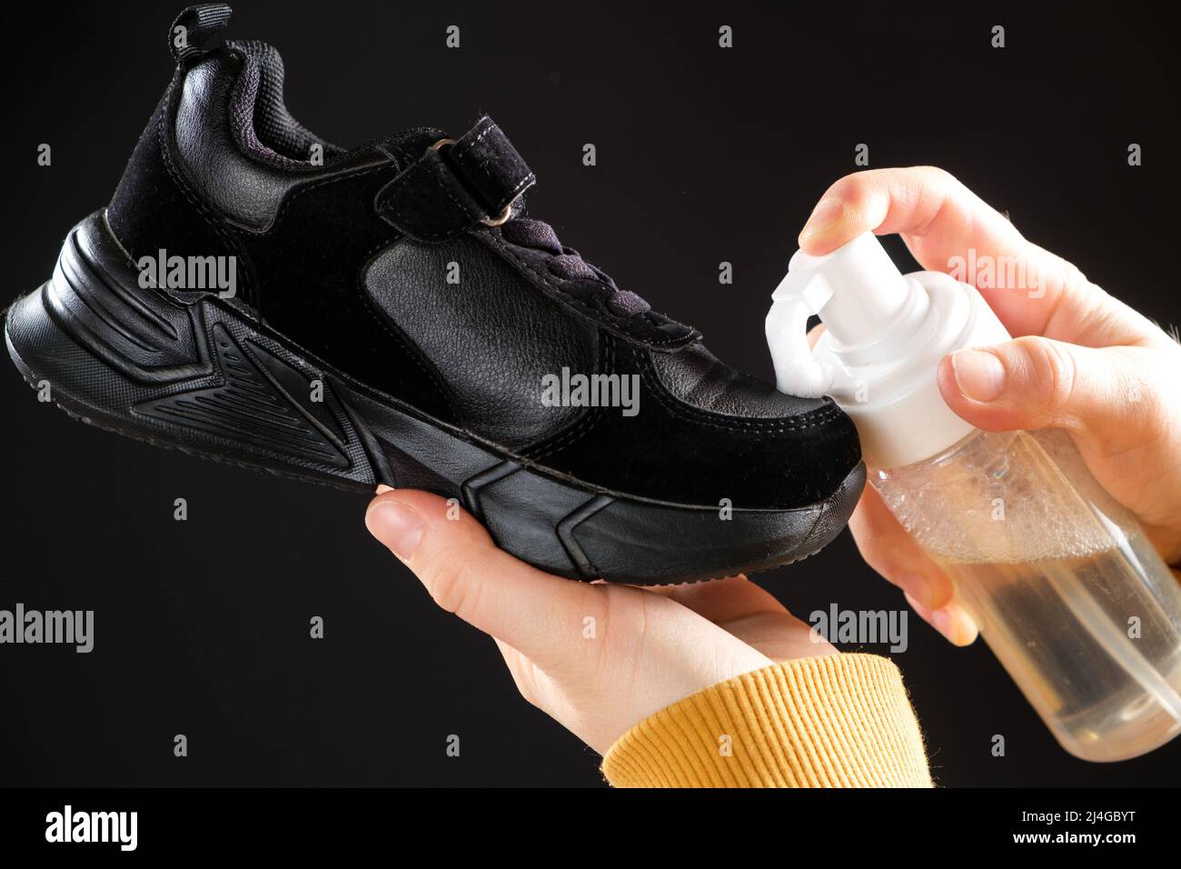Il processo di applicazione della schiuma detergente al briciolo nero del bambino su sfondo nero. Pulizia dei pattini da sporcizia e polvere Foto Stock