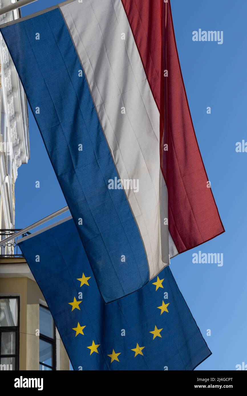 La bandiera olandese e dietro di essa la bandiera dell'Unione europea contro il cielo blu Foto Stock