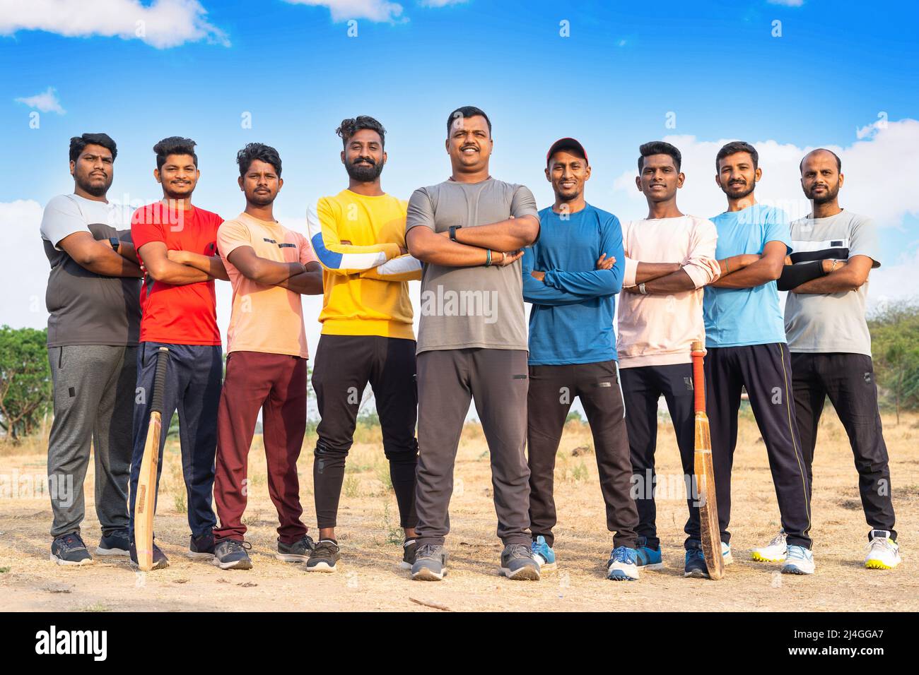 fullshot, un gruppo di giocatori di cricket sicuri in piedi con le braccia incrociate guardando la macchina fotografica al parco giochi - concetto di lavoro di squadra, sportività e. Foto Stock