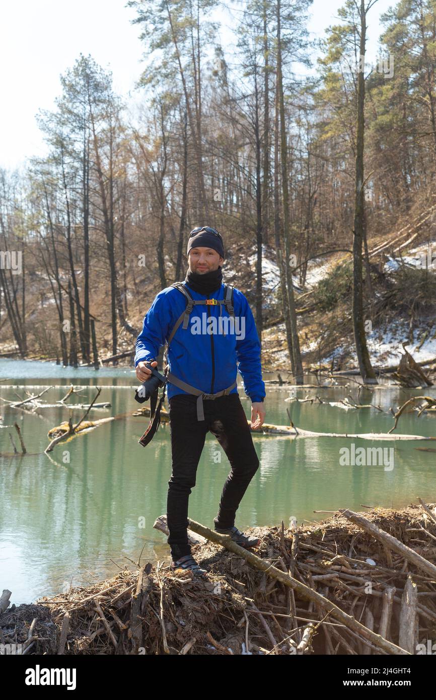 Fotografo con uno zaino sulle spalle e con la fotocamera DSLR nel suo e cammina lungo la diga del castoro e cerca una foto Foto Stock
