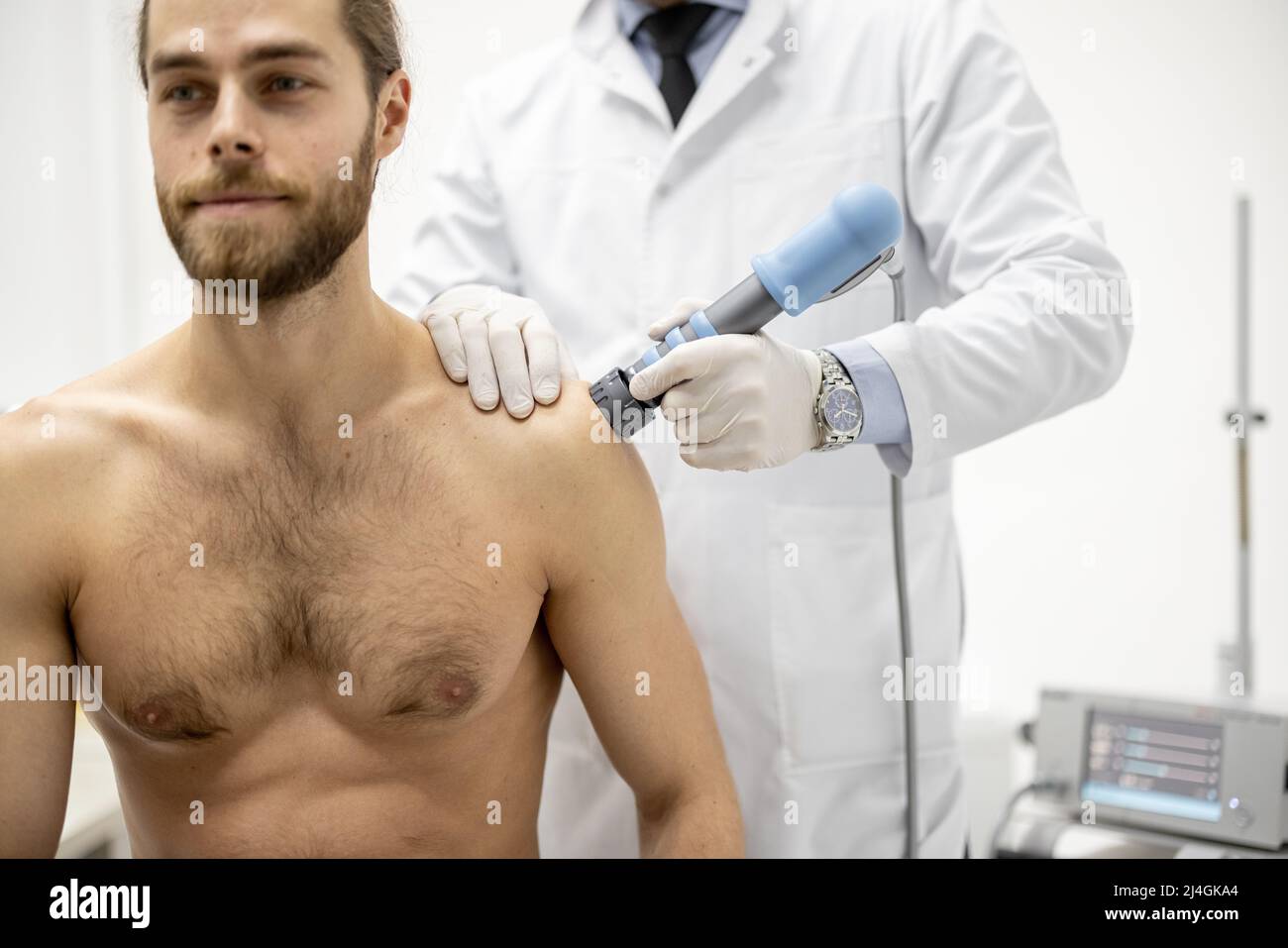 Il medico applica la terapia d'onda d'urto sulla spalla degli uomini Foto Stock