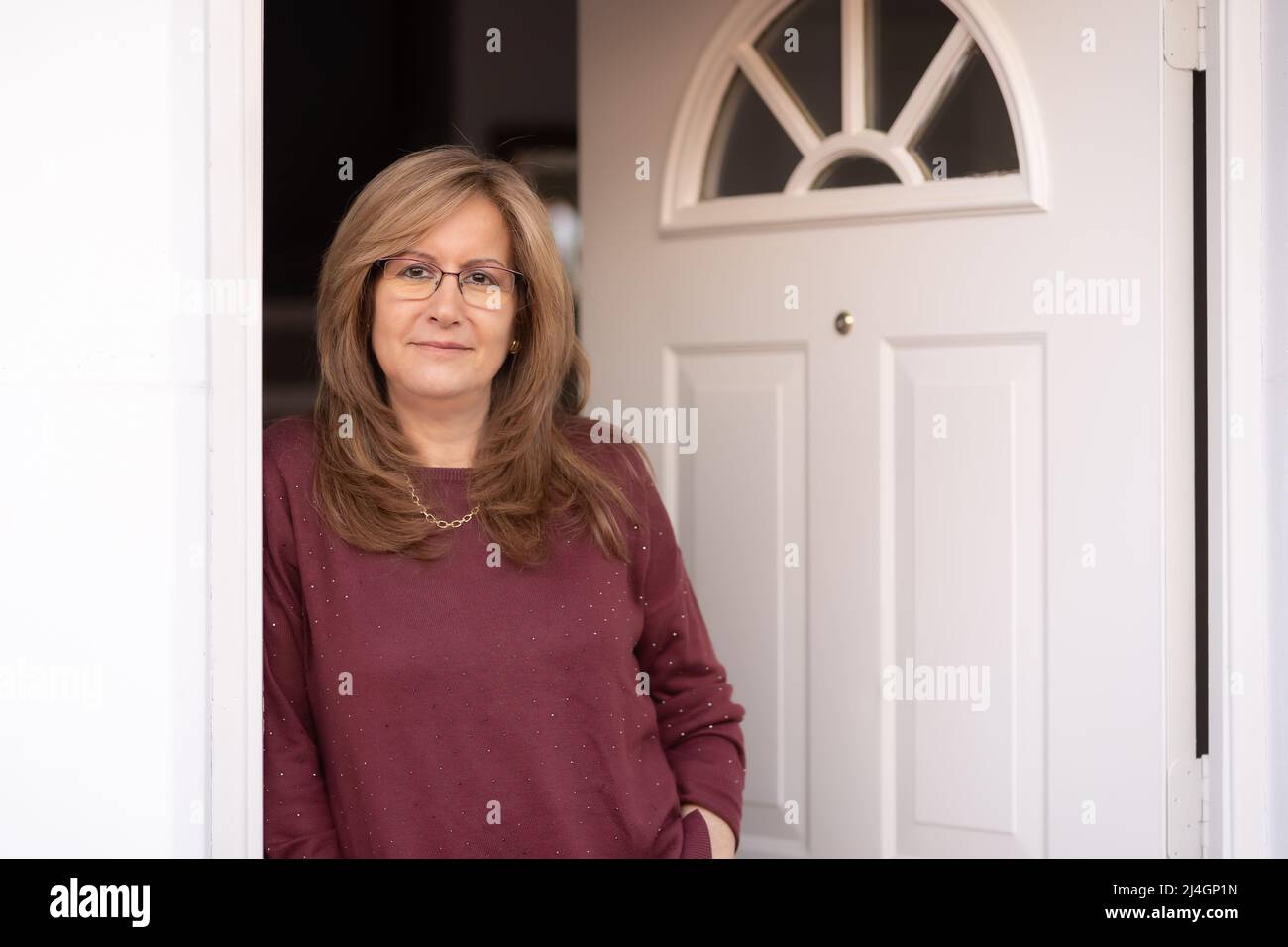 Donna bianca matura alla porta della sua casa in un atteggiamento felice. Foto Stock