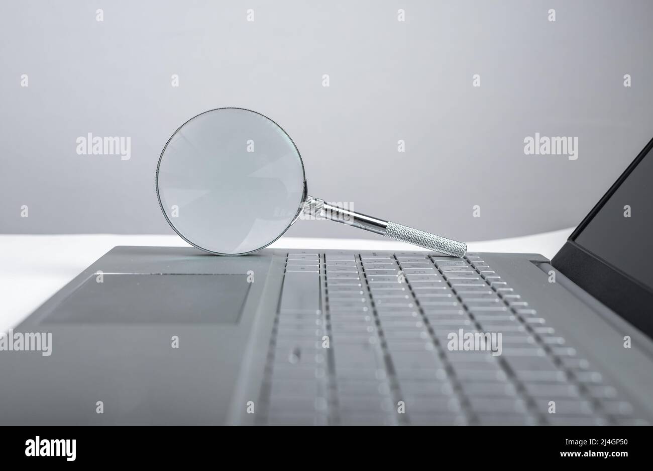 Lente di ingrandimento sulla tastiera del computer portatile. Concetto di ricerca delle informazioni. Controllo dei progetti elettronici, dati finanziari. Foto di alta qualità Foto Stock