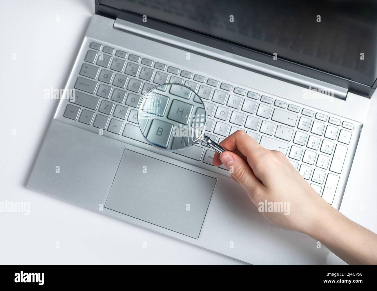 Donna che tiene la lente d'ingrandimento sopra la tastiera del laptop. Ricerca di informazioni su Internet Concept. Esperienza di progetti elettronici, dati finanziari. Foto di alta qualità Foto Stock