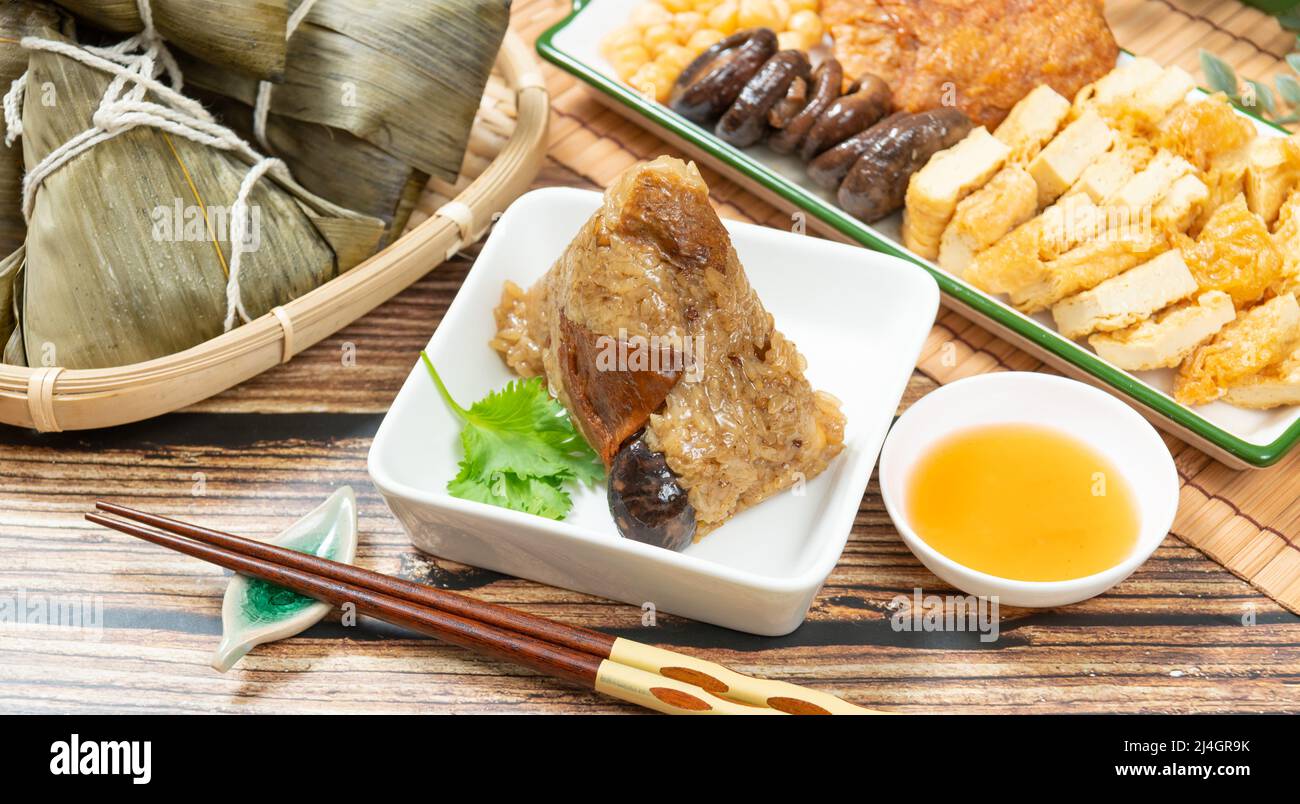 Gnocchi di riso è un piatto di riso cinese tradizionale fatto di riso glutinoso e avvolto in foglie di bambù, Dragon Boat Festival sta facendo e mangiando zongzi Foto Stock
