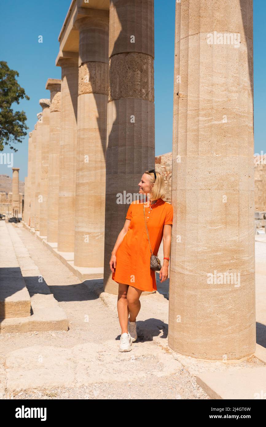 Una donna sorge nell'antica acropoli di Lindos sullo sfondo del colonnato, Grecia, Rodi Foto Stock