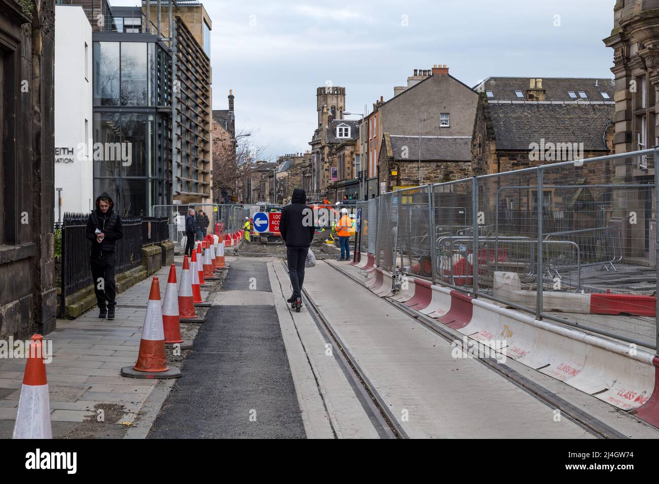 Uomo che guida scooter elettrico su linee di tram durante i lavori di costruzione, Constitution Street, Leith, Edimburgo, Scozia, REGNO UNITO Foto Stock