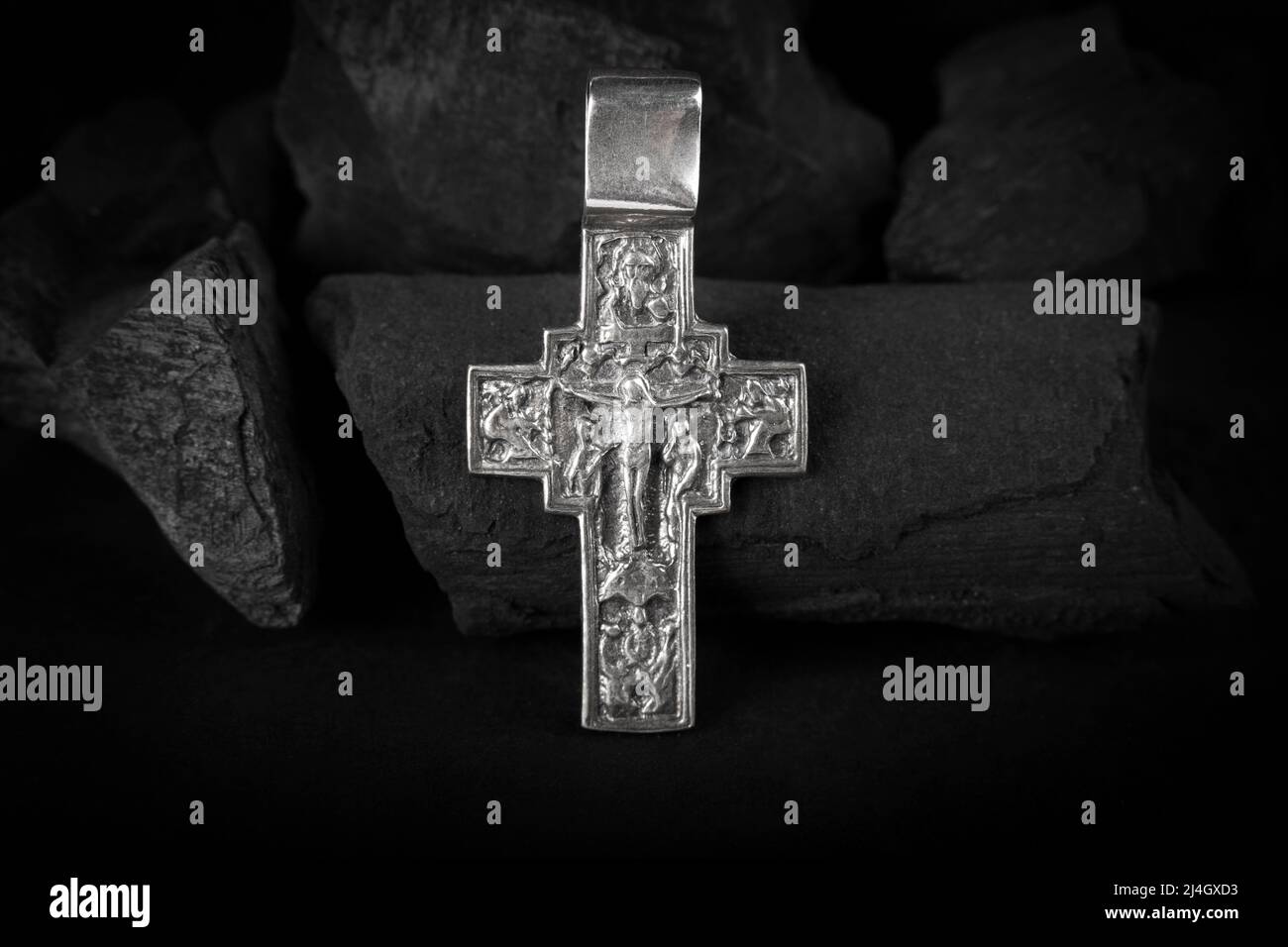 Collana crocefisso in argento su pezzi di carbone. Foto Stock