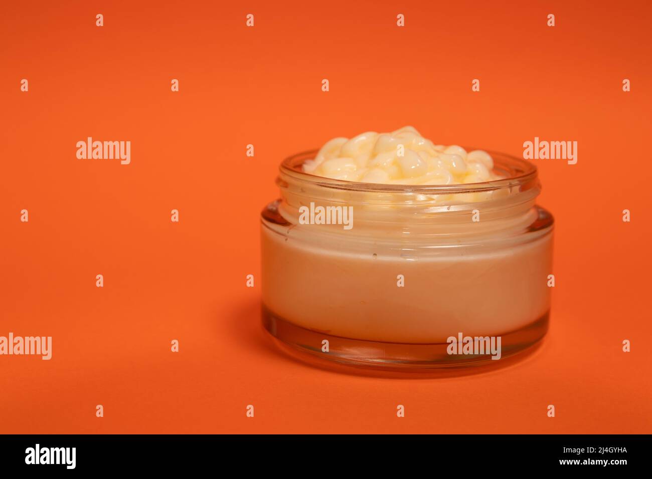 Crema viso in un bicchiere cosmetico su sfondo colorato Foto Stock