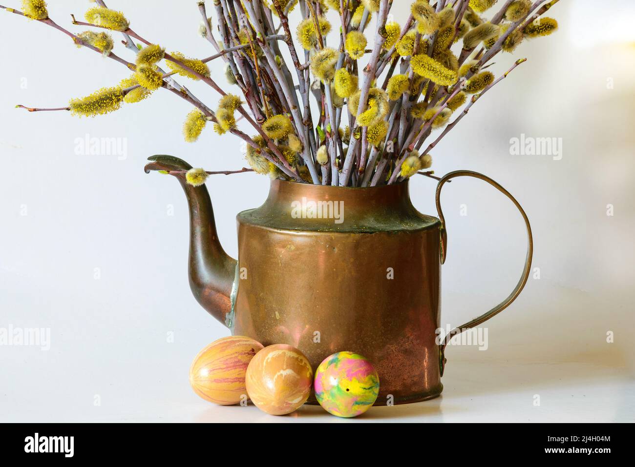 Bella tazza di rame con archi e uova colorate, celebrazione della Pasqua Foto Stock