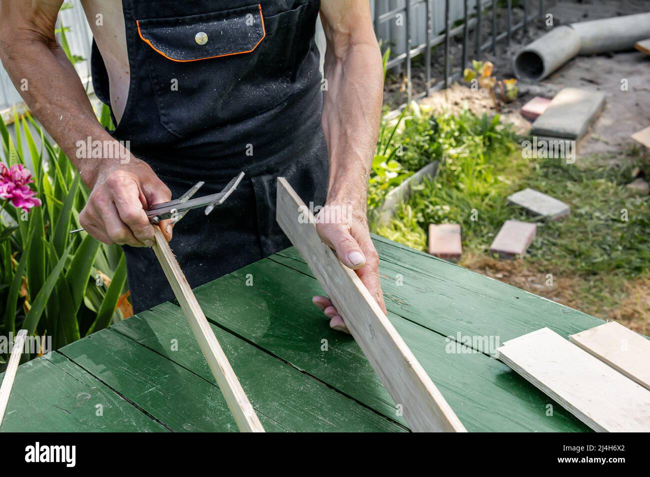 turner misura la tavola con un utensile. Un carpentiere esperto è pronto a tagliare un asse di legno con una sega circolare. Produzione di legno mate Foto Stock