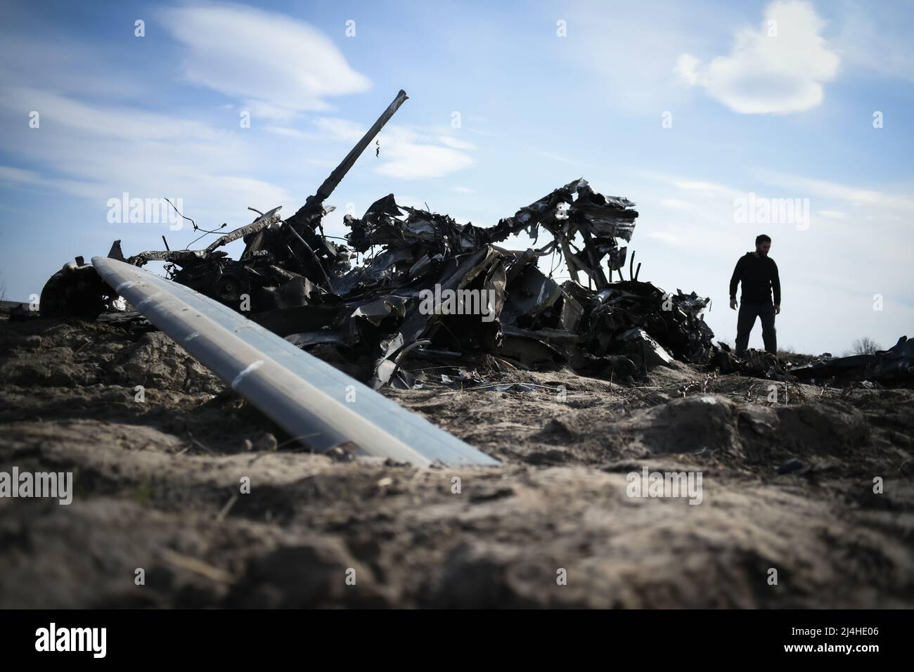 Makariv, vicino a Kiev, Ucraina - 15 aprile 2022: Un uomo cammina accanto al ritiro di un elicottero russo in un campo vicino a Kiev Credit: Piero Crociatti/Alamy Live News Foto Stock