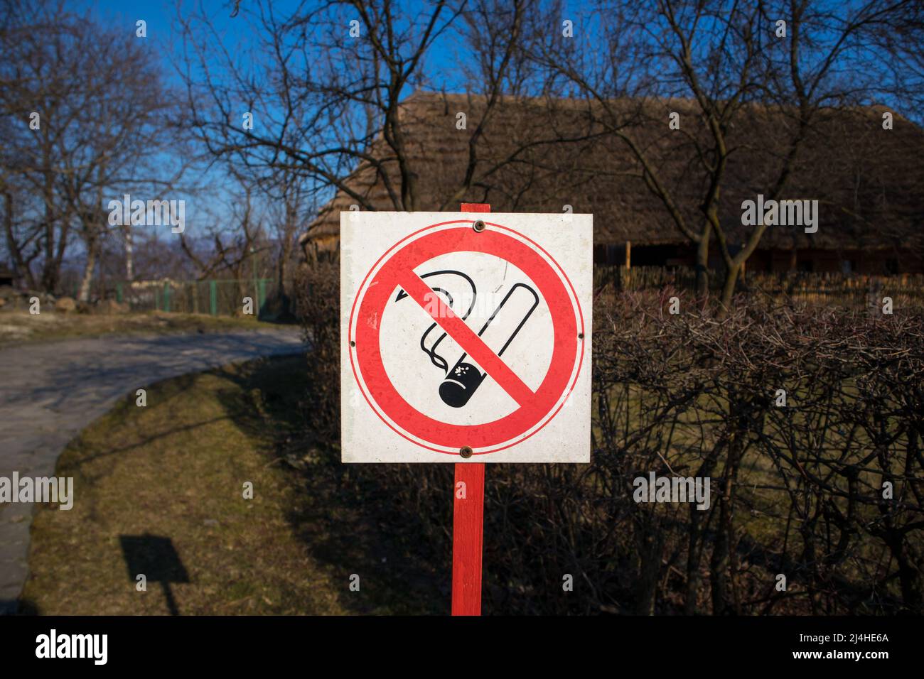 Nessun segno bianco rosso fumante su un post in un luogo pubblico con sfondo naturale sfocato. Cartello bianco con una sigaretta sbarrata su una strada. Icona non consentita Foto Stock