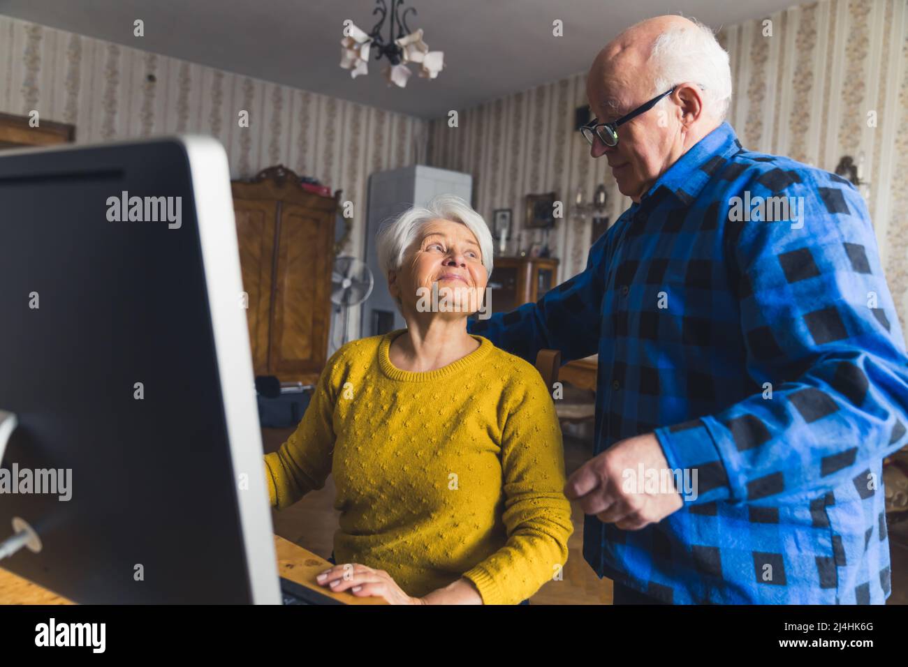 La coppia caucasica del pensionato che fa lo shopping in linea e paga le loro fatture in linea via il calcolatore. Moderno concetto di anziani. Foto di alta qualità Foto Stock