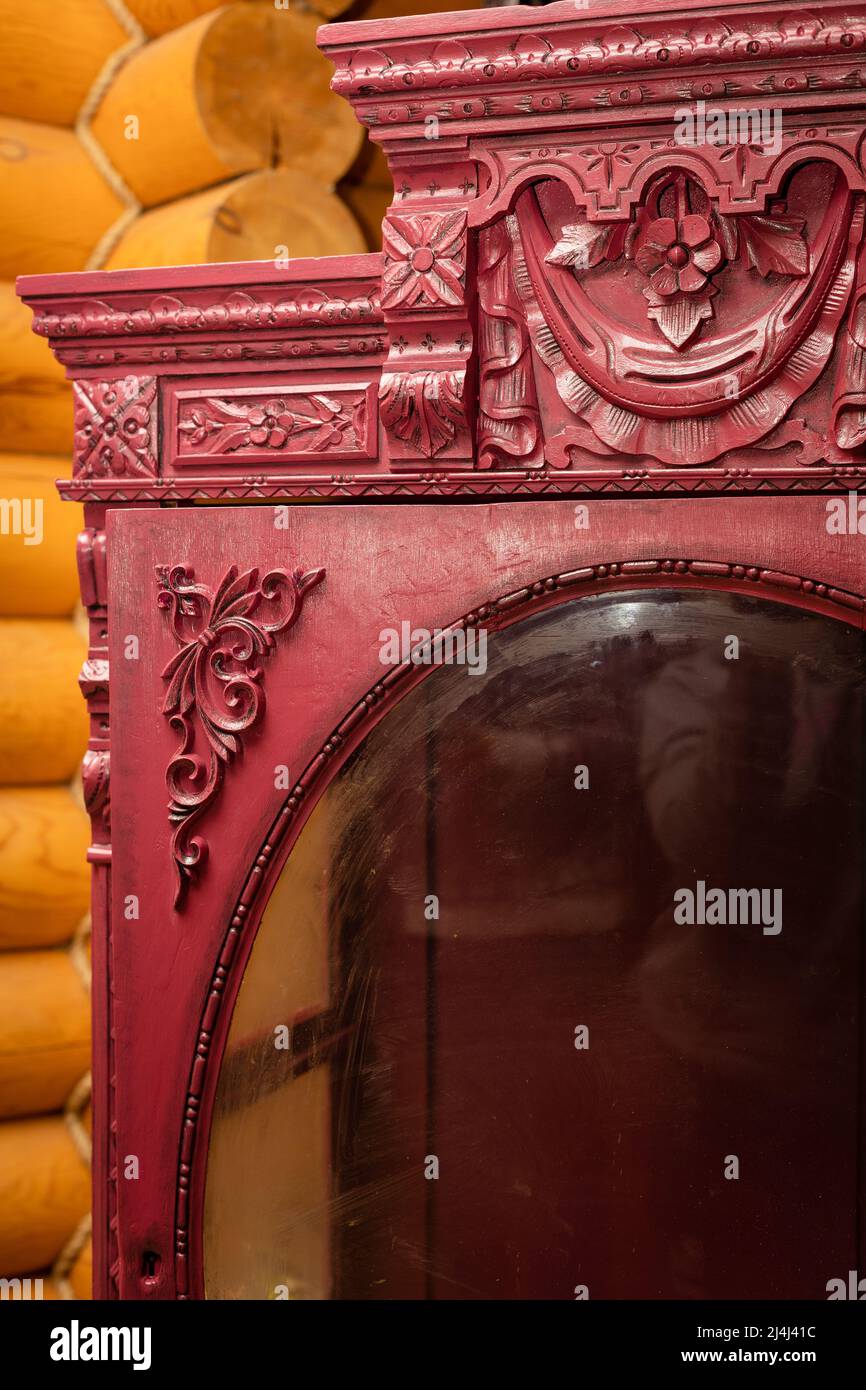 Primo piano di bella vecchia armadio ristrutturato con fantastici ornamenti intagliati a mano con pareti in legno sullo sfondo. Officina per mobili Foto Stock