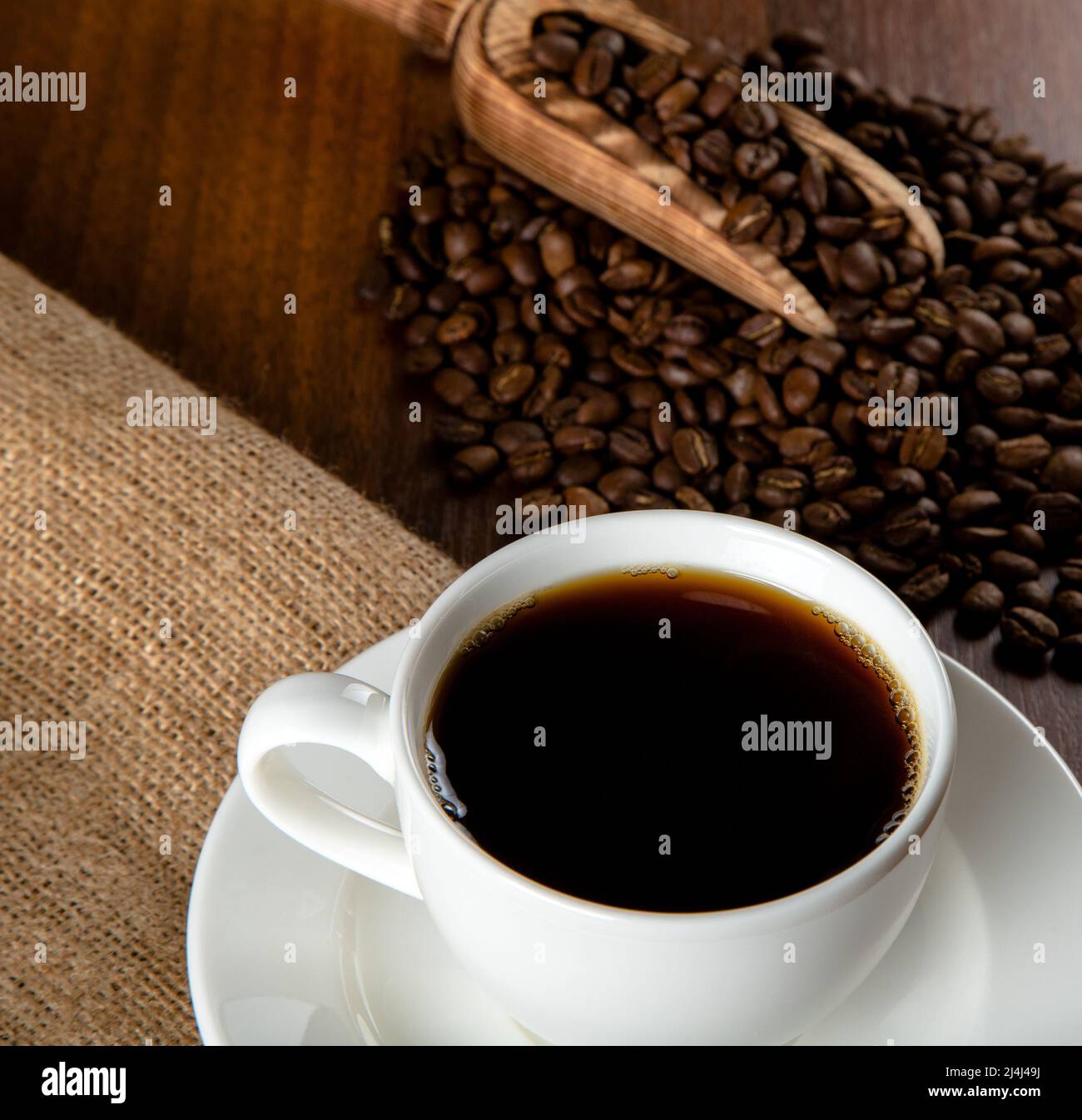 Tazza bianca di caffè con chicchi di caffè su sfondo di legno Foto Stock