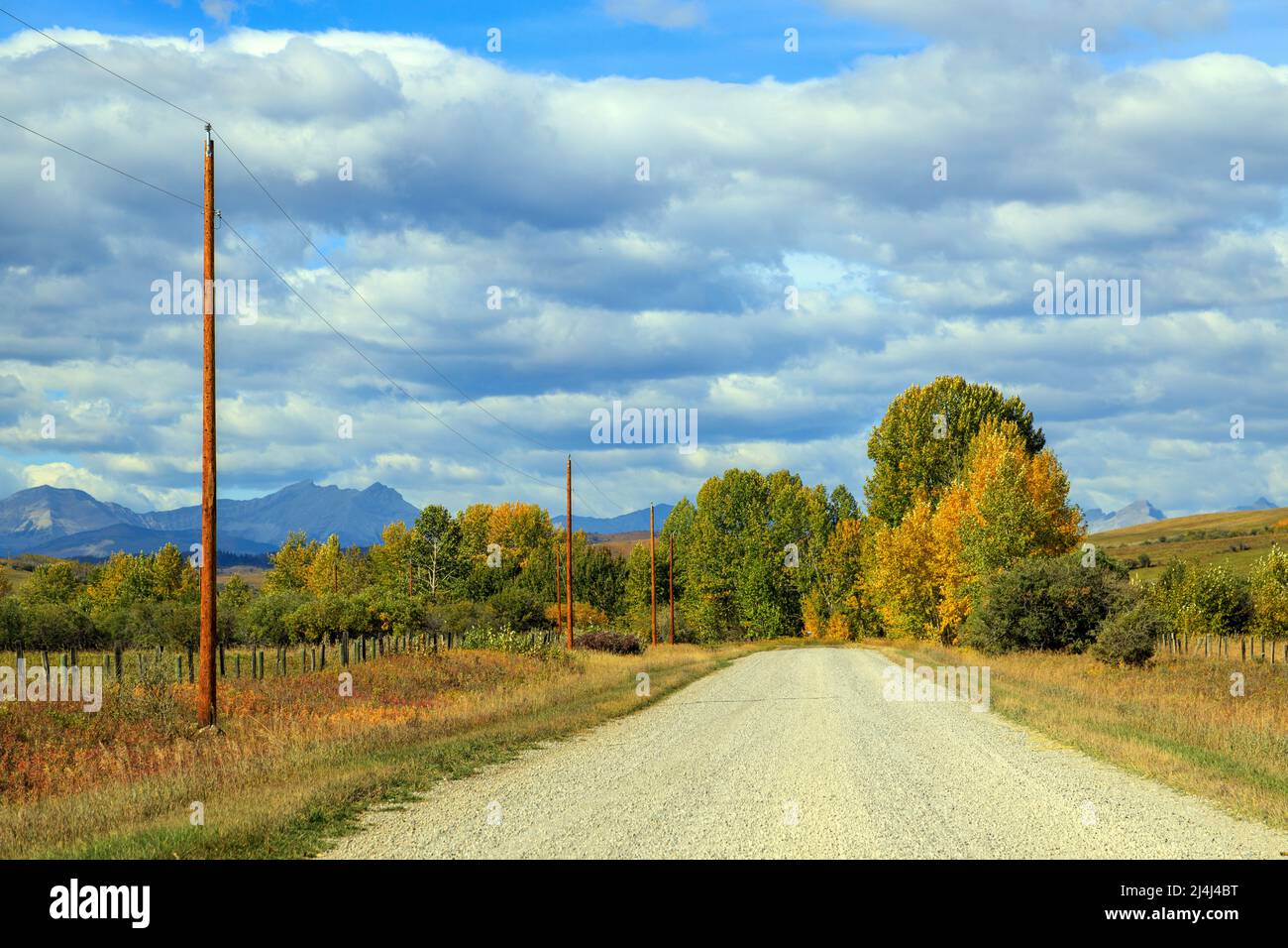 Vista di una strada sterrata di campagna ghiaia ai piedi delle Montagne Rocciose canadesi vicino Turner Valley, Alberta, Canada. Foto Stock